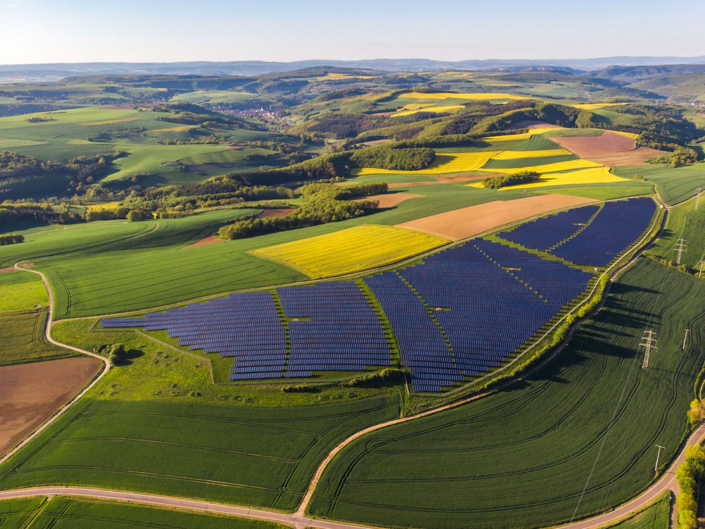 Nachhaltige Investitionen im Bereich Infrastruktur: Photovoltaik-Felder von oben in der Landschaft.
